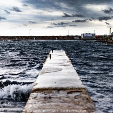 Waves breaking over the harbour wall in Hyères under dark clouds on Day 1 of the SB20 World Championship